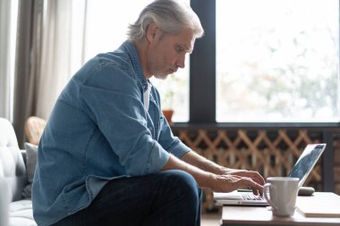 Ev ofisinden bilgisayarda çalışan orta yaşlı bir adam..