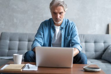 Ev ofisinden bilgisayarda çalışan orta yaşlı bir adam..