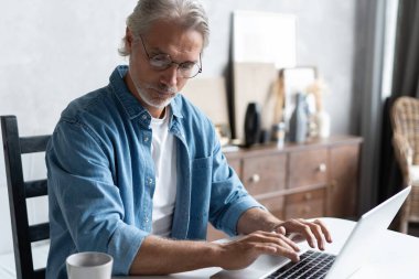 Ev ofisinden bilgisayarda çalışan orta yaşlı bir adam..