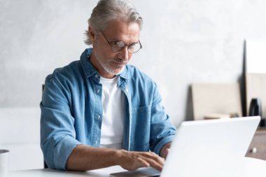 Ev ofisinden bilgisayarda çalışan orta yaşlı bir adam..