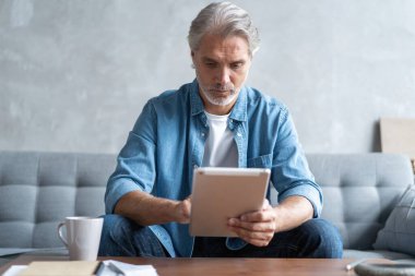 Evden tablet üzerinde çalışan yakışıklı iş adamı.