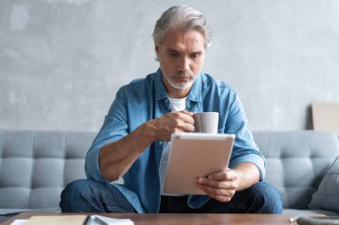 Evden tablet üzerinde çalışan yakışıklı iş adamı.