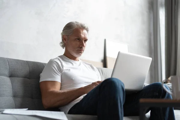 Homem de meia-idade trabalhando de casa-escritório no laptop. — Fotografia de Stock