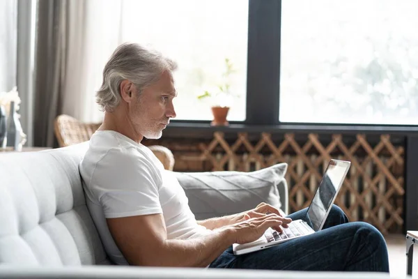 Homem de meia-idade trabalhando de casa-escritório no laptop. — Fotografia de Stock