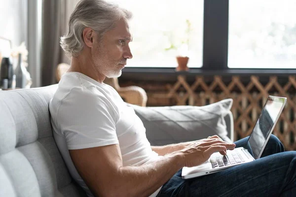 Hombre de mediana edad que trabaja desde casa-oficina en el ordenador portátil. — Foto de Stock