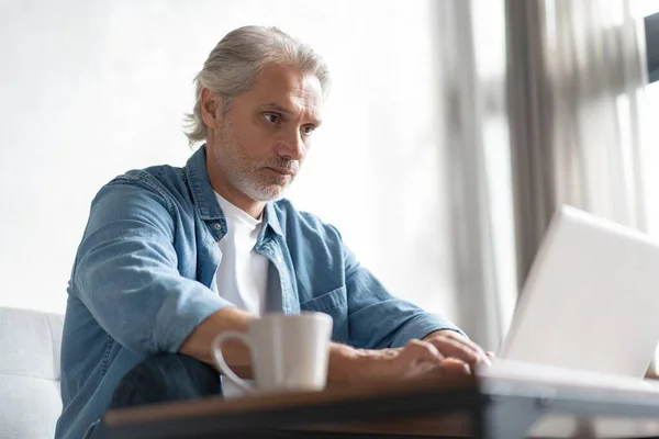 Hombre de mediana edad que trabaja desde casa-oficina en el ordenador portátil. —  Fotos de Stock