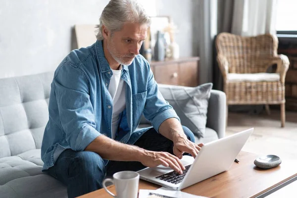 Medelålders man som arbetar från hemmakontoret på laptop. — Stockfoto