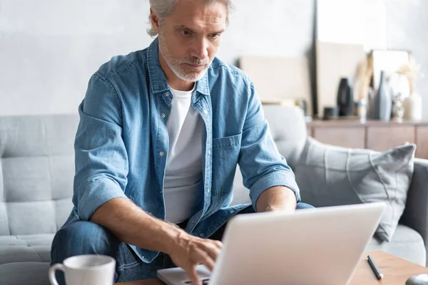 Medelålders man som arbetar från hemmakontoret på laptop. — Stockfoto