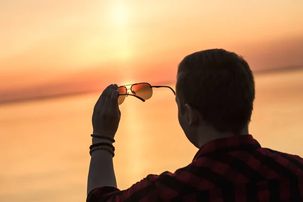 Sonnenuntergang durch Sonnenbrille in Männerhand — Stockfoto