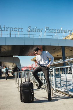 Saint-Petersburg Pulkovo havalimanına taksi çağırmak için smartphone kullanma Bagaj ile yakışıklı bir adam gezgin