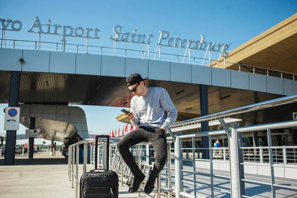 Saint-Petersburg Pulkovo havalimanına taksi çağırmak için smartphone kullanma Bagaj ile yakışıklı bir adam gezgin