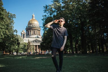 Güneşli yaz günü Saint Isaacs Katedrali, Saint-Petersburg yakınındaki çimenlerin üzerinde yürüyüş turist genç adam.