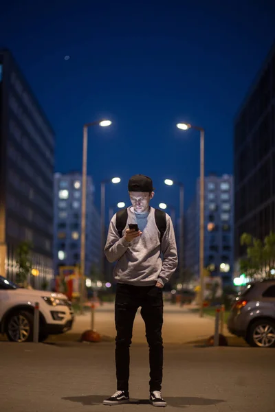 The man phone on the street. Evening night time. Street lights. Telephoto lens shot