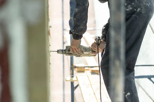 Hand drilling on the scaffolding on altitude. Concept repairing the wall panel — Stock Photo, Image