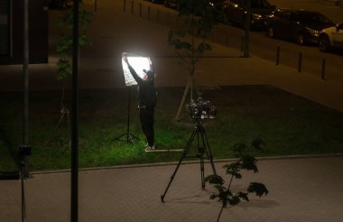 Saint-Petersburg, Rusya, 21.05.2018: adam asistanı video operatörü Spotlight üzerinde bir softbox kurar. Çekim ekipmanları. Geceleri ışık yapma