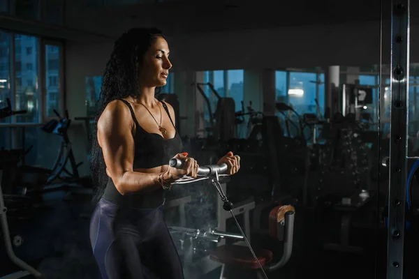 Gyakorlatok blokk szimulátorban. Bicepsz hosszabbítás. Sportos nő edzés tornateremben. — Stock Fotó