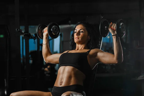 Sportieve brunette vrouw tillen gewichten en werken op haar borst op de sportschool — Stockfoto
