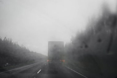 Ön cam ve büyük kamyonda önünde orman yolu üzerinde yağmur damlaları. Araçtan sollama. Düşük görünürlük. Yol emniyet konsepti