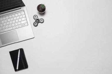 Modern minimalist Ofis veya serbest çalışma alanı. Üstten görünüm. Uzay kopyalayın. Düz yatıyordu. Beyaz masa üzerine kalem ve topluca spinner ile laptop, kaktüs, Not defteri ile kompozisyon