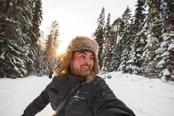 Uomo felice con un cappello di pelliccia godendo della foresta invernale innevata — Foto Stock