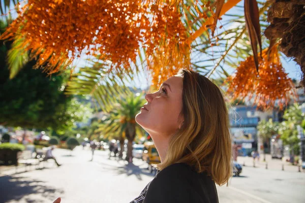 Женщина-туристка ищет сырые финики на пальме. Солнечный свет . — стоковое фото