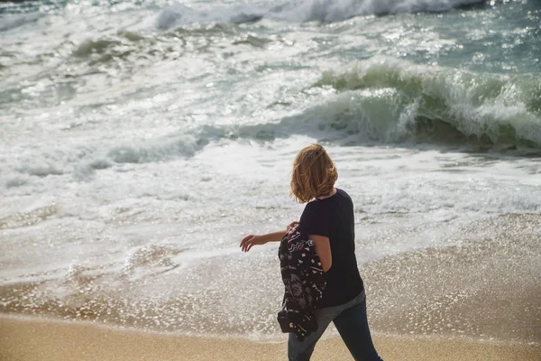 Turista mujer caminando en la costa y mirando al mar tormentoso — Foto de Stock