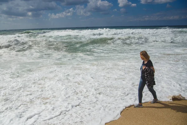 在海岸线上散步的女游客, 望着狂风暴雨的大海 — 图库照片