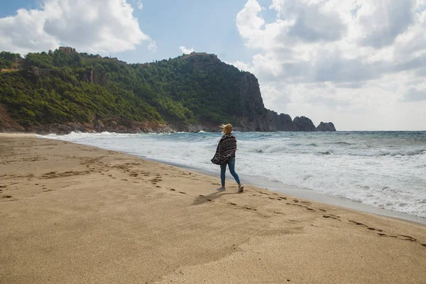 Γυναίκα τουριστικές περπατώντας στην ακτογραμμή και ψάχνει να φουρτουνιασμένη θάλασσα — Φωτογραφία Αρχείου