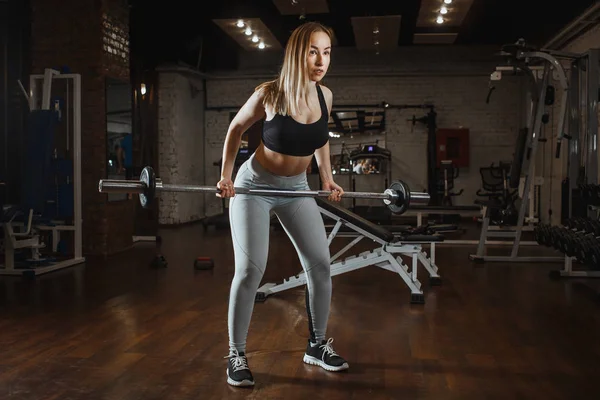 Ung kvinna lyfta skivstång med lätta vikter på gym. Fitness kvinnliga crossfit träning — Stockfoto