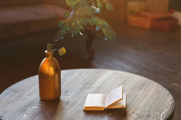 Кавовий столик, ваза з гілочкою і старою книгою на сонячному світлі — стокове фото