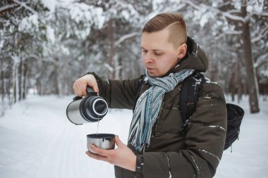 Bir termos dolusu bir karlı kozalaklı ormanda sıcak çay ile şık adam