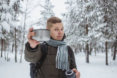 Bir termos dolusu bir karlı kozalaklı ormanda sıcak çay ile şık adam