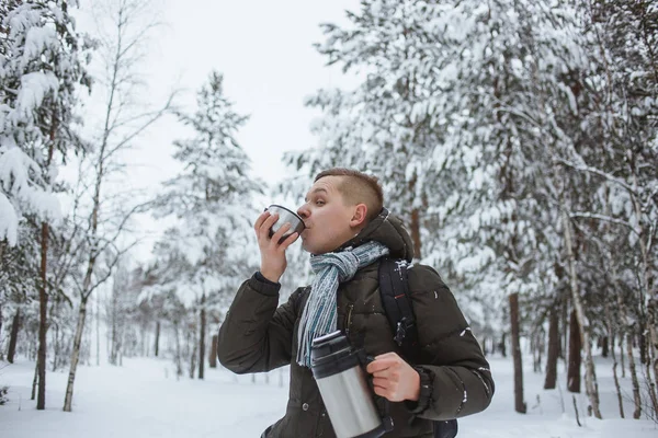 Bir termos dolusu bir karlı kozalaklı ormanda sıcak çay ile şık adam — Stok fotoğraf