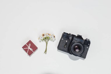 Minimalist düz beyaz arka plan üzerinde kompozisyon retro kamera, vinous hediye kutusu ve bahar alan çiçek ile yatıyordu. Trendy düz mockup blogcular, tasarımcılar, fotoğrafçılar, vb koymak