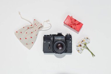 Retro kamera, kırmızı hediye kutusu ile minimalist düz yatıyordu kompozisyon çanta kırmızı kalp şekillerle tuval ve beyaz arka plan üzerinde alan çiçek bahar. Trendy düz mockup blogcular, tasarımcılar için lay