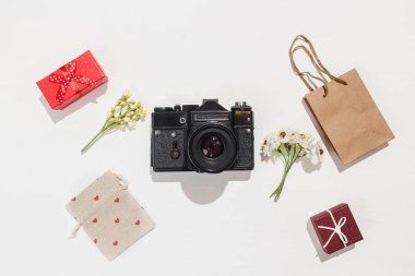 Minimalist düz yatıyordu kompozisyon retro kamera, kırmızı hediye kutuları, zanaat çanta, çanta kırmızı kalp şekillerle tuval ve beyaz arka plan üzerinde alan çiçek bahar. Trendy düz mockup blogcular için lay