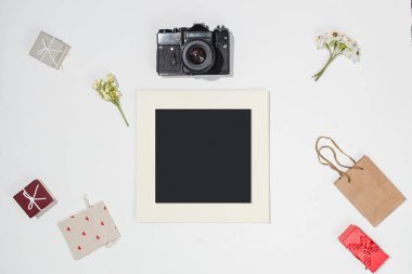 Kompozisyon siyah fotoğraf çerçevesi, retro kamera, kırmızı hediye kutuları, zanaat çanta, çanta kırmızı kalp şekillerle tuval ve beyaz arka plan üzerinde alan çiçek bahar. Trendy düz mockup blogcular için lay