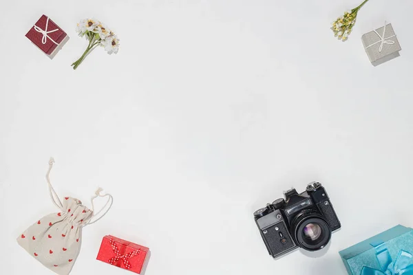 Весняний макет подарункової картки для фотографів. Пласка композиція з ретро камерою, червоними, сірими та синіми подарунковими коробками, полотно сумки з червоними формами серця та весняними квітами на білому тлі — стокове фото