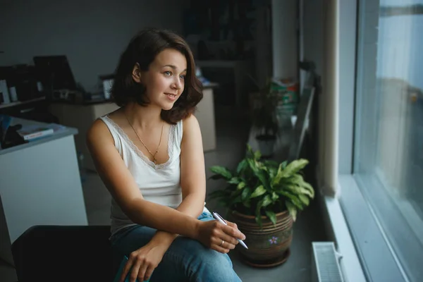 Joven mujer de negocios mirando a la ventana en la oficina . — Foto de Stock