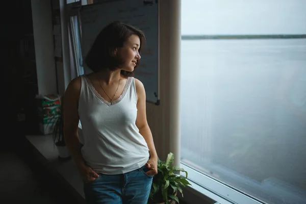 Joven mujer de negocios en ropa casual mirando a la ventana en la oficina — Foto de Stock