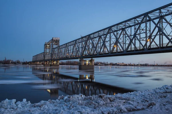 Beautiful view of ice drift under the railway bridge in Arkhangelsk, Russia. Beautiful ice motion on Northern Dvina river, evening landscape