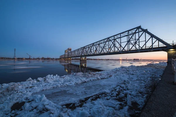 Pemandangan indah es melayang di bawah jembatan kereta api di Arkhangelsk, Rusia. Indah gerak es di Utara Dvina sungai, lanskap malam Stok Lukisan  