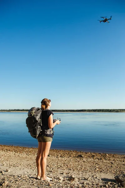 Vrouwelijke toeristische controleren de drone met de afstandsbediening. Rivier shore locatie — Stockfoto