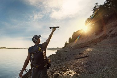 Erkek turist dron elinden içinde güzel gün batımı woodland içinde başlatılması.