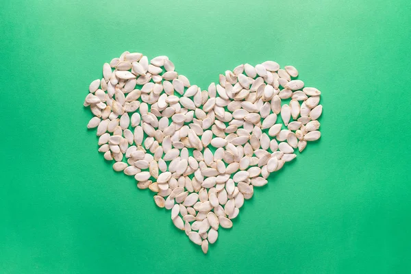 Forma de corazón de semillas de calabaza sobre fondo verde. Redacción plana minimalista — Foto de Stock