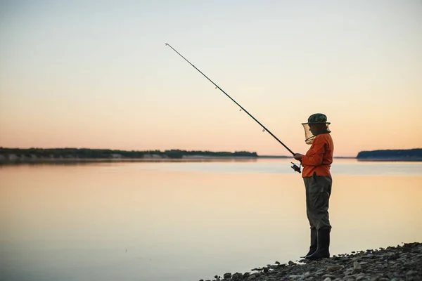 Mujer joven en la pesca de mosquiteros con caña de pescar en la noche — Foto de Stock