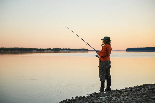 Mujer joven en la pesca de mosquiteros con caña de pescar en la noche — Foto de Stock