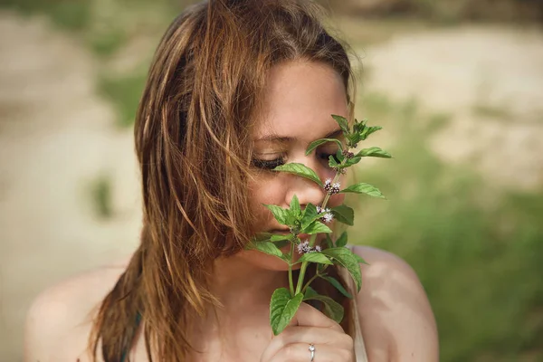 Beautiful woman smelling aroma of melissa grass in her hand. — Stock Photo, Image