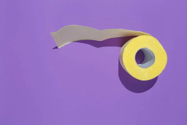 Желтый рулон туалетной бумаги на фиолетовом фоне. Плоская композиция — стоковое фото