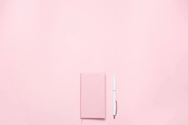 Escritorio de color rosa con diario de color rosa y pluma blanca. Composición plana minimalista con espacio de copia para blogueros, diseñadores, revistas, etc. — Foto de Stock